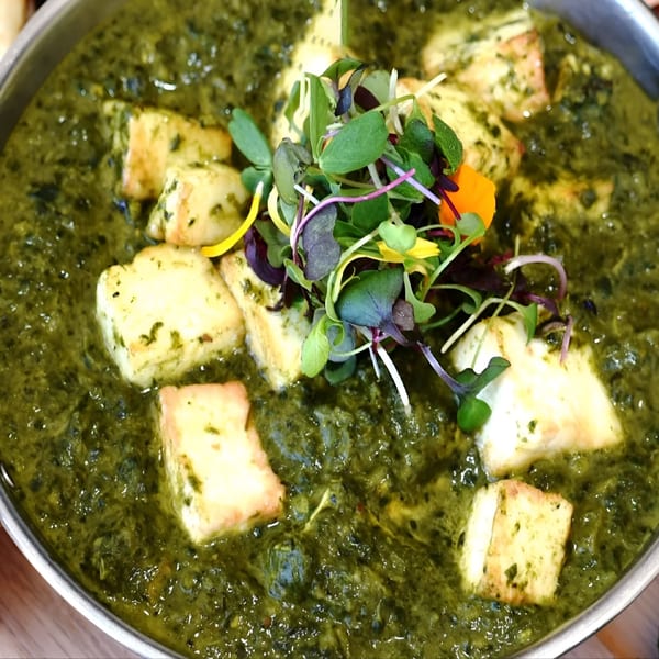 Close-up of Everest Curry And MoMo House's vibrant green Palak Paneer, garnished with fresh microgreens.